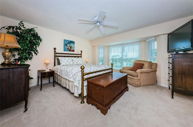 bedroom with ceiling fan, baseboards, a textured ceiling, and light colored carpet