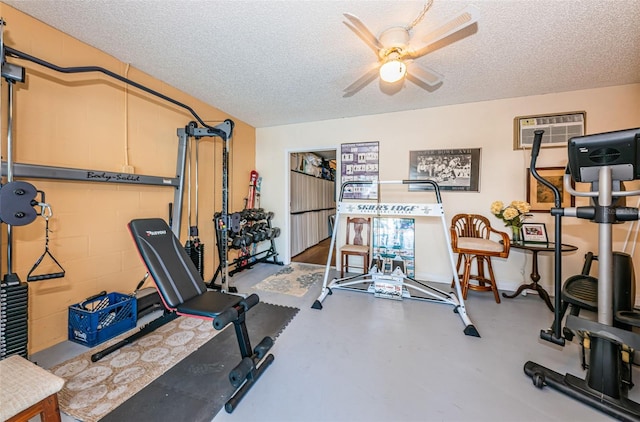 workout room with a ceiling fan, a wall mounted air conditioner, and a textured ceiling