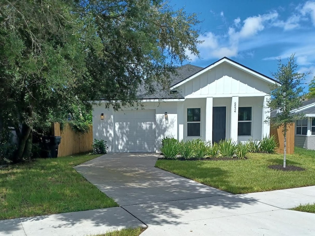 view of front of house with a garage, fence, driveway, a front lawn, and board and batten siding