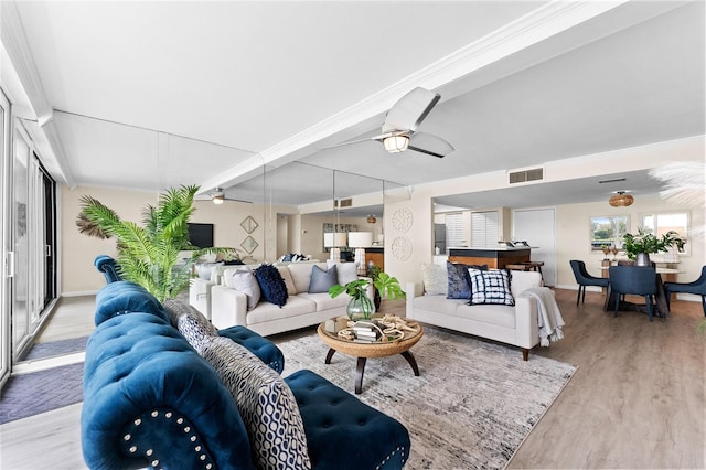 living room featuring beam ceiling, light wood-type flooring, ceiling fan, and crown molding