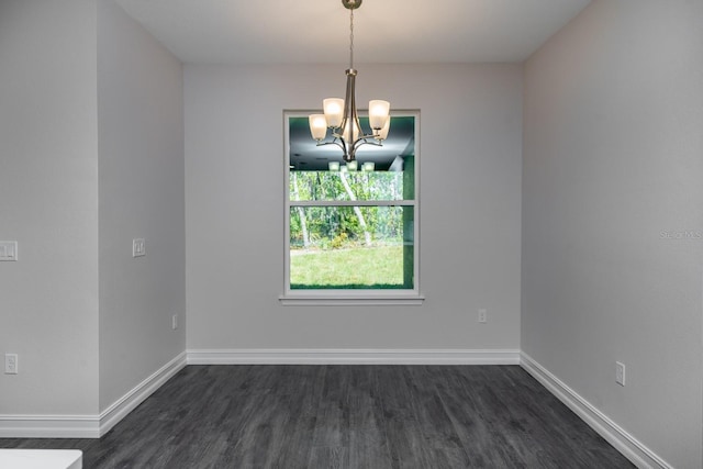 empty room with dark wood-type flooring and a chandelier