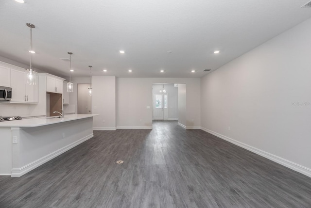 kitchen with white cabinets, pendant lighting, dark hardwood / wood-style floors, and a large island with sink