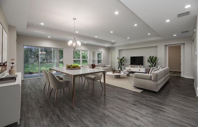 dining area featuring a chandelier, a tray ceiling, and dark hardwood / wood-style flooring