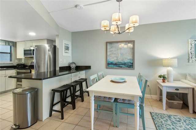 kitchen featuring a notable chandelier, a breakfast bar, stainless steel appliances, and light tile patterned floors