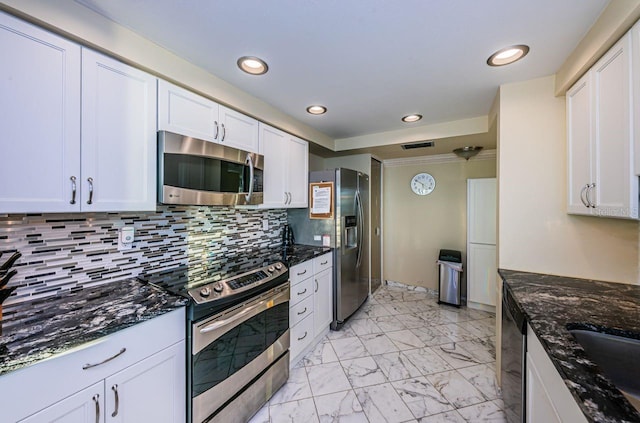 kitchen with dark stone countertops, decorative backsplash, white cabinets, and appliances with stainless steel finishes