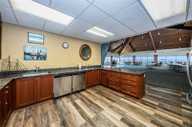 kitchen featuring stainless steel dishwasher, kitchen peninsula, sink, and dark stone countertops