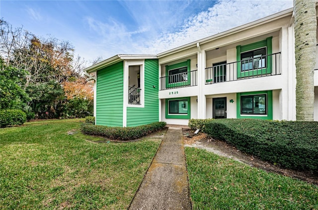 view of front of home with a balcony and a front lawn