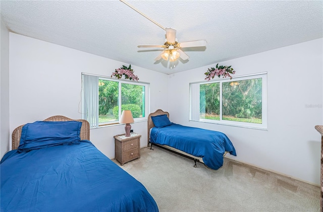 carpeted bedroom featuring a textured ceiling, ceiling fan, and multiple windows