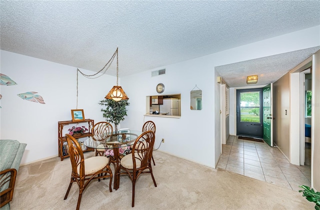 dining area featuring light colored carpet and a textured ceiling