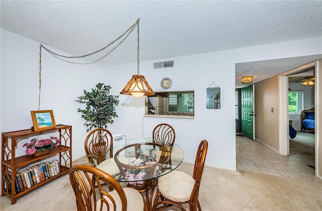 carpeted dining room with a textured ceiling and ceiling fan