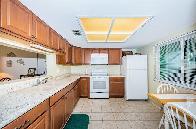 kitchen with white appliances, sink, light stone countertops, and light tile floors