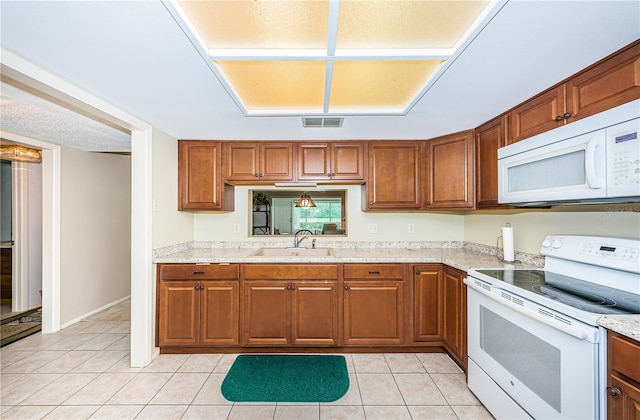 kitchen featuring light tile floors, light stone counters, white appliances, and sink