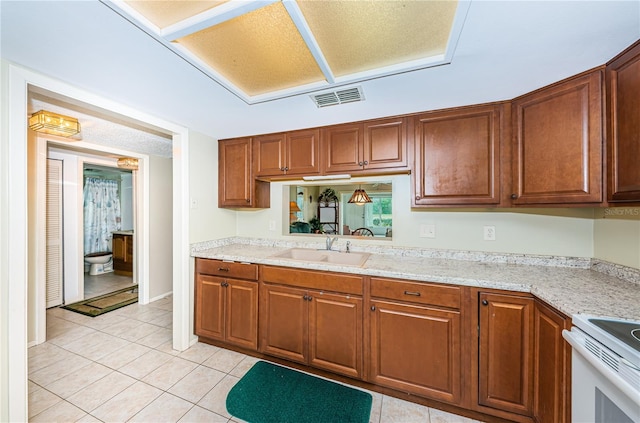 kitchen with light tile floors, light stone countertops, sink, and white stove