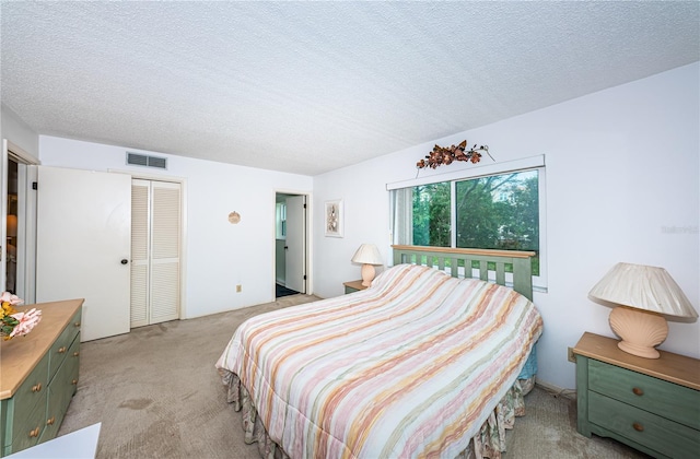 bedroom featuring a closet, light carpet, and a textured ceiling