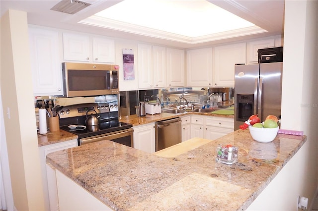 kitchen with white cabinets, stainless steel appliances, sink, kitchen peninsula, and light stone counters