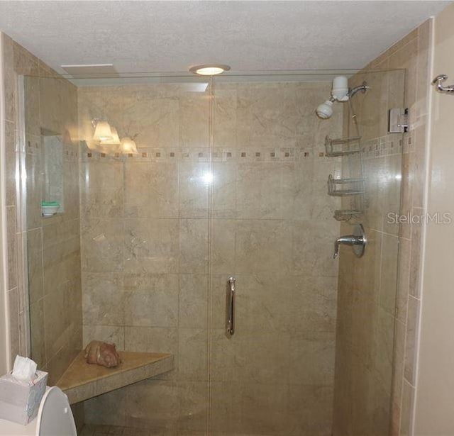 bathroom with toilet, a textured ceiling, and walk in shower