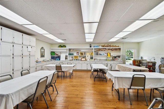 dining area with a drop ceiling and light hardwood / wood-style flooring