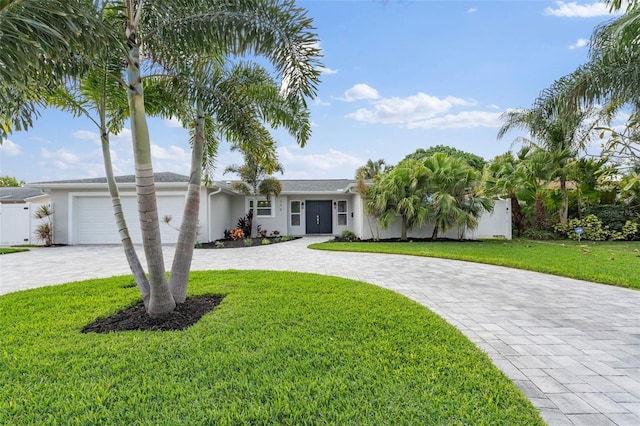 view of front facade with an attached garage, a front lawn, decorative driveway, and stucco siding