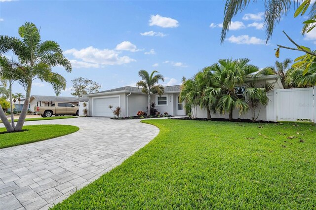 view of front facade featuring a garage, fence, decorative driveway, a front yard, and stucco siding