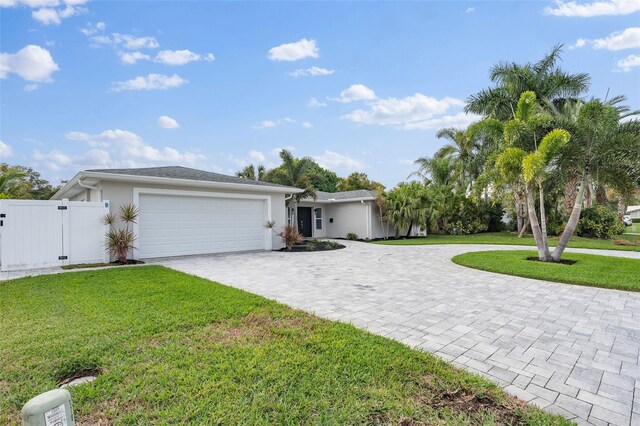 single story home with a garage, a front lawn, decorative driveway, and a gate