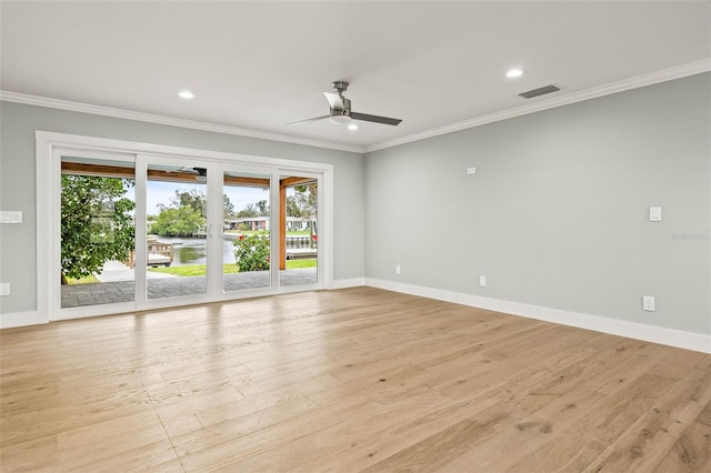 spare room featuring baseboards, light wood finished floors, visible vents, and crown molding