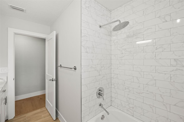 bathroom featuring wood finished floors, vanity, visible vents, baseboards, and  shower combination