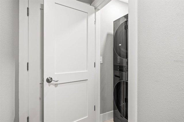 laundry room with a textured wall, stacked washer and dryer, and laundry area