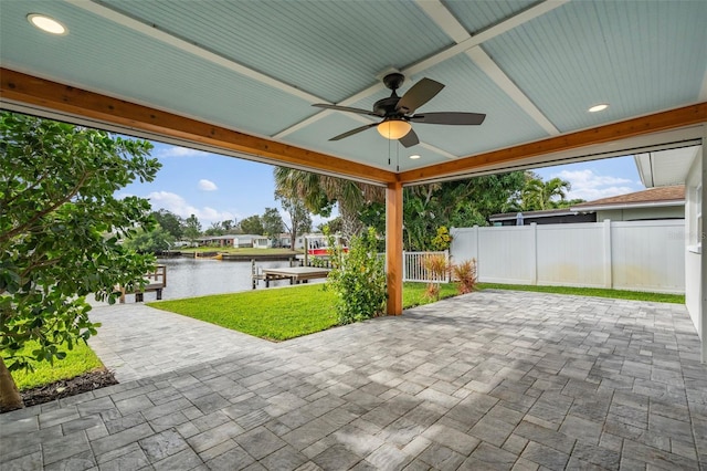 view of patio / terrace featuring a water view, a dock, fence, and a ceiling fan