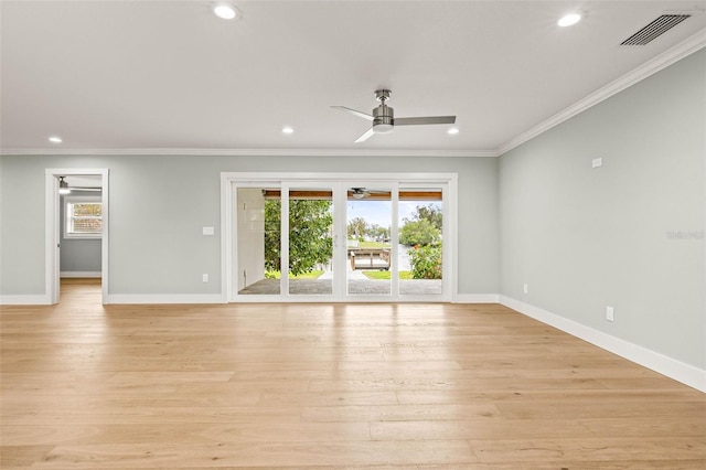 spare room with ornamental molding, visible vents, plenty of natural light, and light wood finished floors