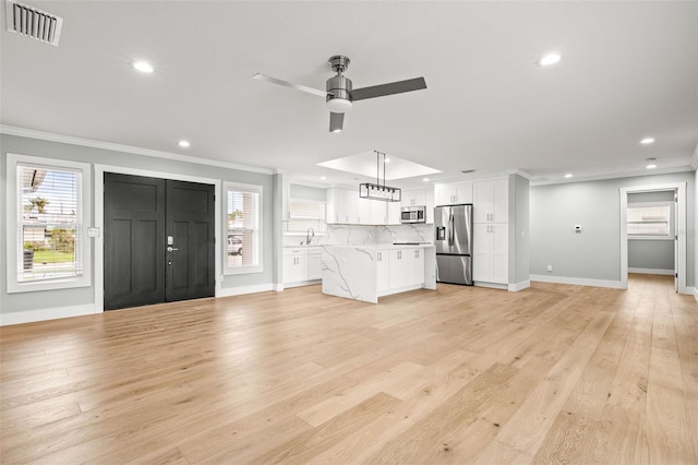 unfurnished living room featuring crown molding, visible vents, plenty of natural light, and light wood finished floors