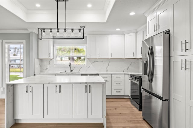 kitchen featuring white cabinetry, range, stainless steel fridge with ice dispenser, a tray ceiling, and crown molding