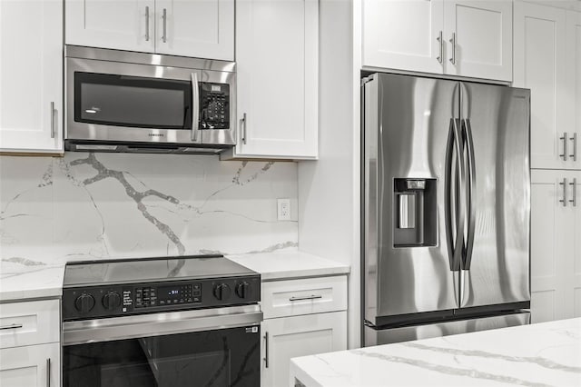 kitchen with light stone counters, appliances with stainless steel finishes, white cabinets, and decorative backsplash