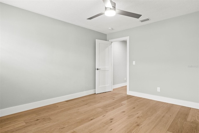 empty room with light wood-type flooring, baseboards, visible vents, and a ceiling fan