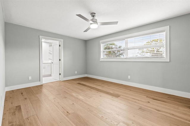 spare room featuring light wood-type flooring, ceiling fan, baseboards, and a textured ceiling