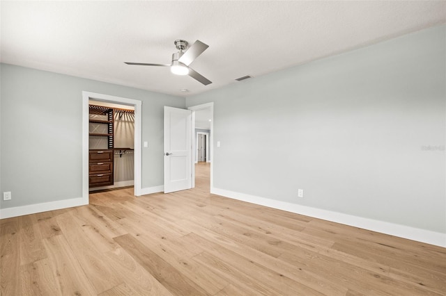 unfurnished bedroom featuring a closet, visible vents, light wood-style flooring, ceiling fan, and baseboards