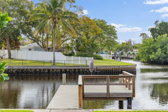 view of dock with a water view, fence, and a lawn