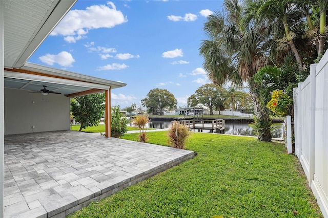 view of yard with ceiling fan, a patio area, a water view, and fence