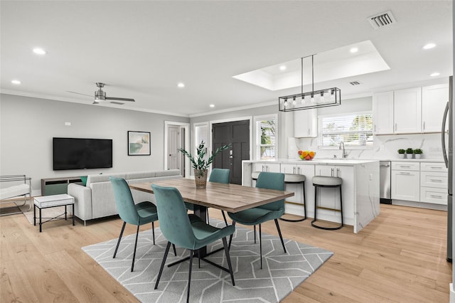 dining area featuring ornamental molding, visible vents, and light wood-style floors