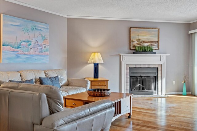 living room featuring light wood-type flooring, crown molding, and a textured ceiling