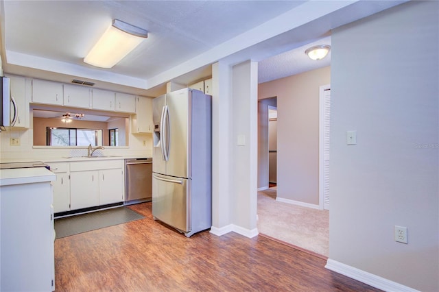 kitchen with appliances with stainless steel finishes, dark hardwood / wood-style floors, and white cabinets