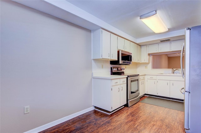 kitchen with sink, tasteful backsplash, appliances with stainless steel finishes, dark hardwood / wood-style flooring, and white cabinets