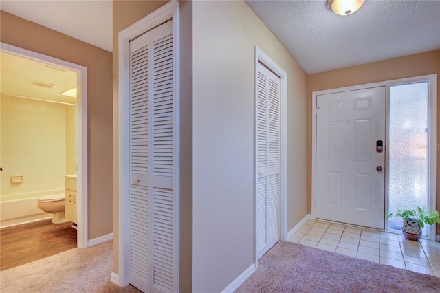 entrance foyer featuring light carpet and a textured ceiling