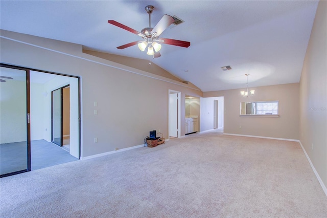 empty room featuring ceiling fan with notable chandelier, light colored carpet, and vaulted ceiling