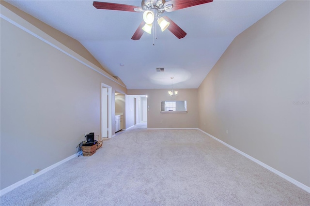 spare room featuring lofted ceiling, ceiling fan with notable chandelier, and light carpet