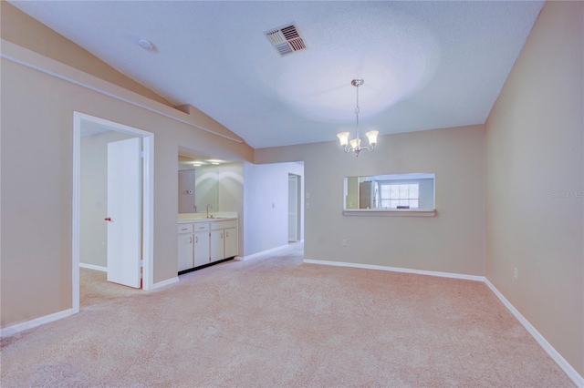 spare room featuring sink, vaulted ceiling, light carpet, and a notable chandelier