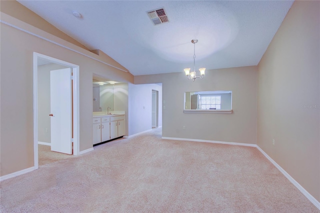 unfurnished dining area featuring light colored carpet, sink, a chandelier, and vaulted ceiling