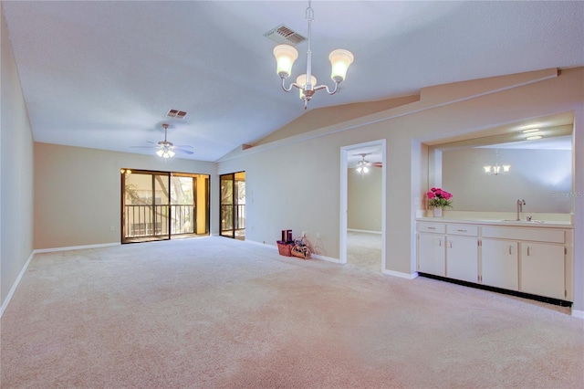 unfurnished living room featuring sink, ceiling fan with notable chandelier, vaulted ceiling, and light colored carpet