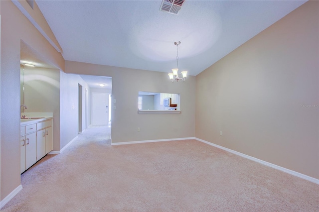 empty room with a chandelier, sink, and light carpet