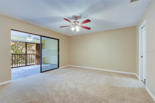 empty room with ceiling fan, light colored carpet, and a textured ceiling