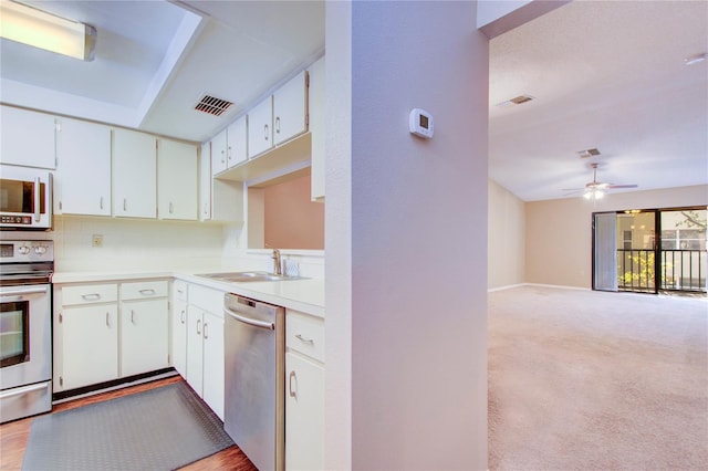 kitchen with sink, white cabinetry, light carpet, stainless steel appliances, and decorative backsplash